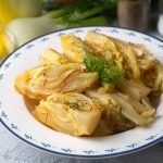 Finocchi alla mediterranea al forno, morbidi e profumati 1 In primo piano un piatto di finocchi alla mediterranea con del finocchietto selvatico.